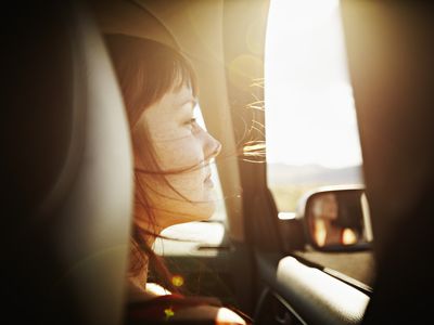 Woman with hair blowing looking out window of car