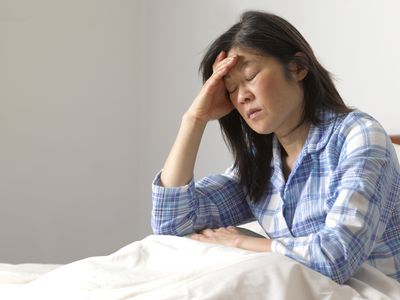 Woman with migraine headache in bed