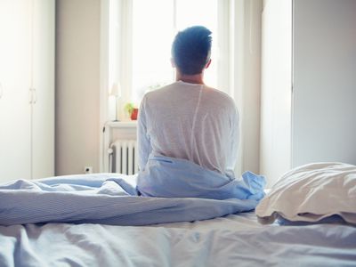 Young man sitting on bed