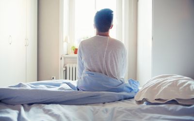 Young man sitting on bed