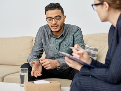 Person in counseling session sits on couch in therapist office.