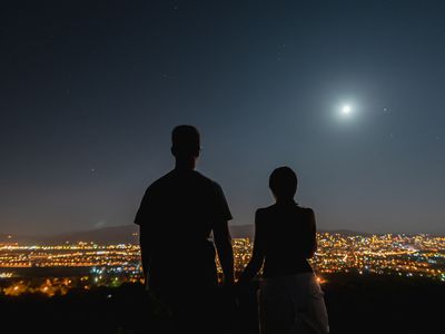 silhouette of a girl with a view of the city with a full moon