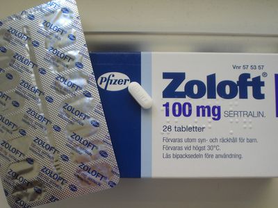 Box of Zoloft with one pill sitting on the package. 